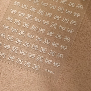 Détail des stickers d'ongles avec nœuds blancs et numéro de modèle YT490-2 sur carte