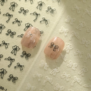 Macro shot of minimalist black and white bow nail stickers with subtle rhinestone details