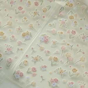 Macro detail of 3D embossed tulip and rose flower nail art stickers in pastel colors