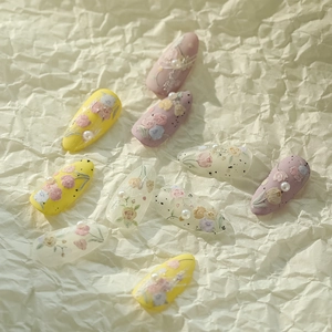Detailed view of handmade floral press-on nails with 3D pearls and tulip designs