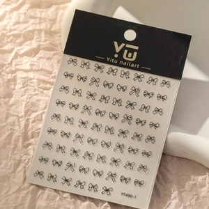 Détail de stickers à ongles nœuds noirs présentés sur un plateau décoratif minimaliste