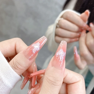 Detail of light pink gradient coffin press-on nails with white floral patterns and glitter