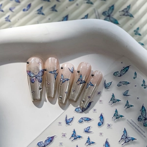 Detail of blue 3D butterfly nail stickers and silver gradient fake nails with crystals