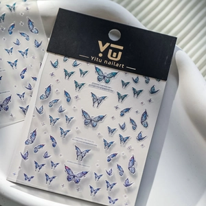 Close-up of blue butterfly 3D nail stickers with starry elements and cursive typography