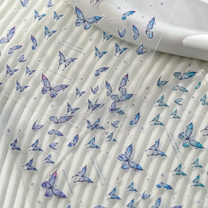 Macro detail of 3D embossed blue butterfly nail stickers with sparkling star elements
