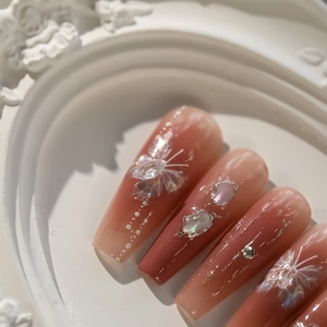 Detailed view of pink butterfly press-on nails with shell pieces and rhinestones