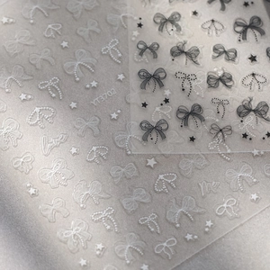Macro shot of 5D embossed nail art stickers with lace bows and pearl star details