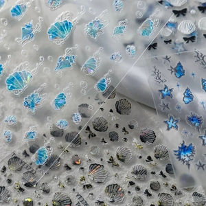 Macro detail of holographic ocean themed nail stickers with seashells and starfish designs