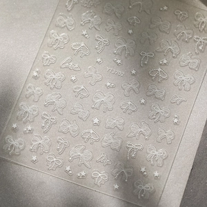 Close-up of 5D white lace bow and star embossed nail stickers with love text