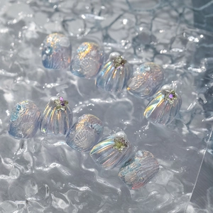 Macro view of ocean themed iridescent 3D embossed shell and pearl press-on nail set