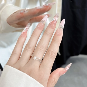 Detail of pink and white gradient stiletto nails with floral patterns and pearls