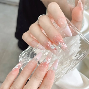 Detail of pink gradient stiletto press-on nails with delicate flower and rhinestone accents