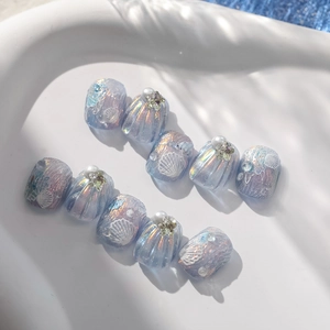 Detail of aurora ocean press-on nails with blue shells and pearls in a tray