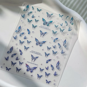 Detail of 3D embossed blue butterfly nail stickers with purple stars on a white tray