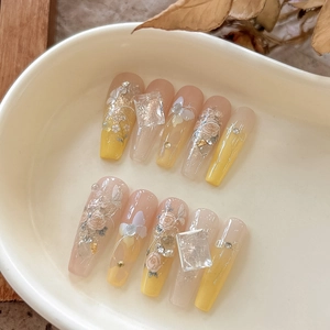 Detail of yellow gradient long coffin fake nails with 3D roses and pearls on a plate