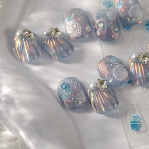 Macro shot of 3D shell seashell nail art tips with iridescent laser finish and pearls