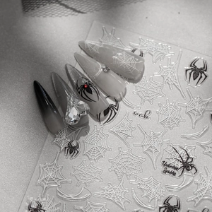 Detail of gothic stiletto fake nails with spider web stickers and crystal heart jewelry