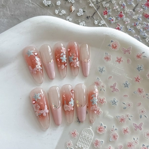 Detail of almond nails with pink floral patterns and tiny rhinestones in a tray