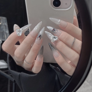 Macro view of long stiletto press-on nails featuring silver glitter and spider web designs