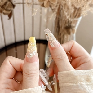 Close-up of yellow gradient coffin press-on nails with 3D floral art, pearls and rhinestones