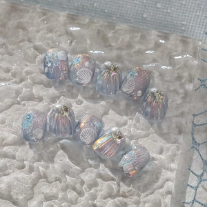 Macro shot of 3D shell texture, pearls and starfish on aurora blue ocean style fake nails