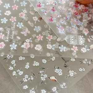 Macro view of embossed nail stickers with watercolor flowers, butterflies and birds