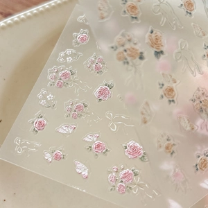 Macro detail of 3D embossed rose and butterfly nail stickers with embroidery texture