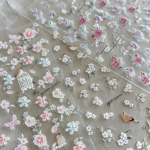 Close-up of floral embossed nail art stickers with peach blossoms, butterflies and birds