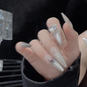 Detailed view of long stiletto press-on nails with 3D heart gems and spider web patterns