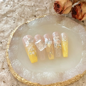 Detailed macro shot of 3D embossed floral nail charms with pearls and gold foil accents