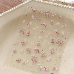Detailed close-up of 5D embossed nail stickers with pink roses and white butterflies