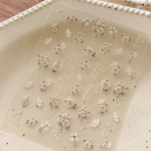 Macro detail of 5D embossed nail stickers with pink roses, butterflies and 3D floral textures