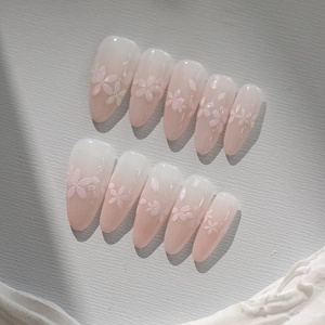 Detail of pink ombré almond press-on nails with 3D embossed cherry blossoms and glitter