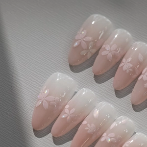 Detailed macro view of 3D pink cherry blossom nail charms on long gradient stiletto press-on nails