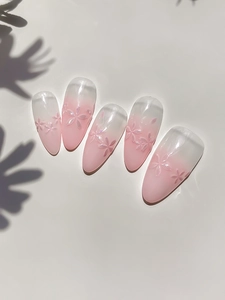 Detailed view of pink ombre almond press-on nails with 3D embossed cherry blossoms