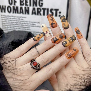Detailed view of Halloween press-on nails featuring pumpkin, bat and ghost patterns