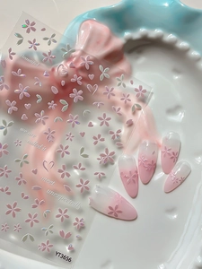 Macro shot of 3D pink cherry blossom nail stickers with iridescent shell luster and hearts