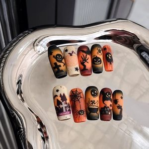 Macro detail of coffin-shaped Halloween nail art with pumpkin and ghost motifs