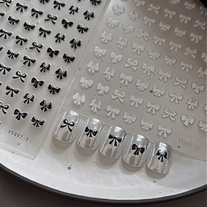 Detail of 3D embossed black and white bow nail stickers showing texture on silver nails