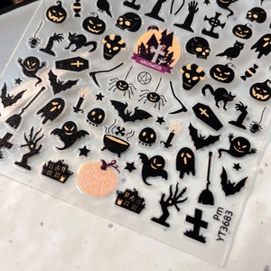 Macro shot of Halloween nail decals with golden pumpkins, ghosts, and bats, model Pm YT3683