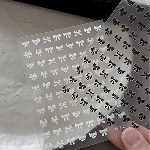 Detail of 3D embossed bow nail stickers in black and white with realistic relief texture