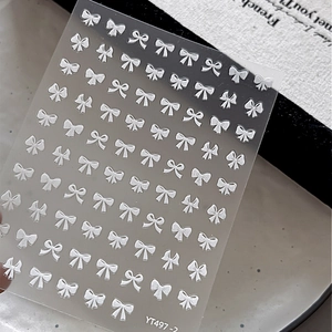 Detailed macro view of silver 3D embossed bow tie nail art stickers with metallic finish
