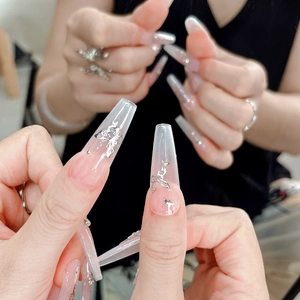 Dettaglio unghie coffin con sfumatura rosa, farfalle argentate e decorazioni di strass