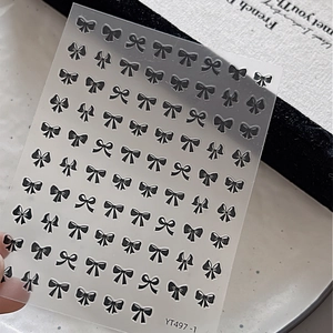 Close-up of YT497-1 nail stickers featuring black bow patterns and 3D relief effects