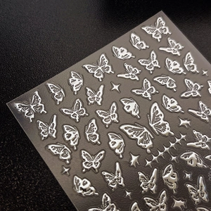 Dettaglio di adesivi per unghie a farfalla in argento metallizzato con piccoli riflessi