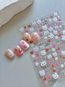 Detail view of cute rabbit and strawberry nail stickers on natural manicured nails