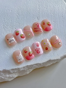 Detailed view of short round press-on nails with 3D cat paw and strawberry designs