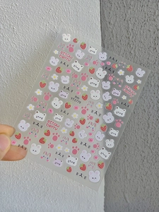 Detail view of cute cartoon nail stickers featuring rabbits, cats, and strawberries