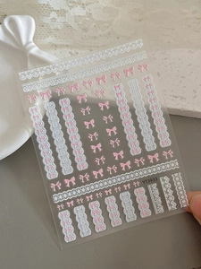 Détail de stickers à ongles nœuds roses avec motifs dentelle blanche pour manucure DIY