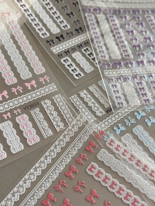 Vue macro de stickers nail art 3D gaufrés avec motifs dentelle et nœuds colorés